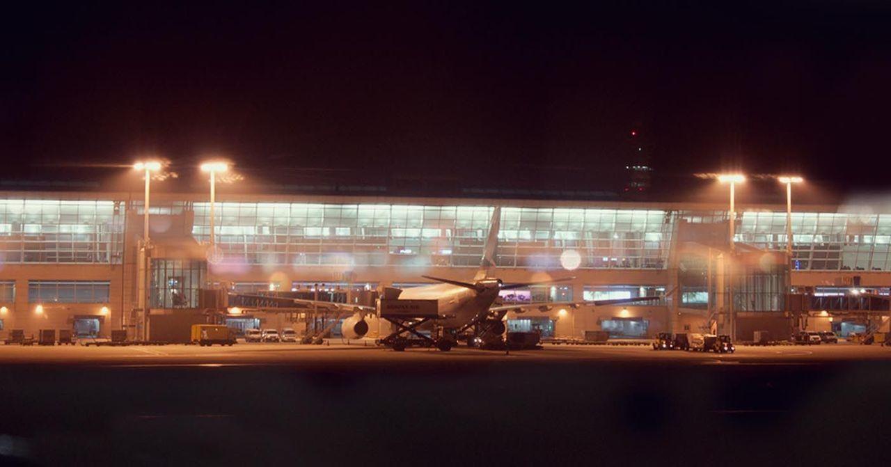 Night view of Incheon International Airport terminal with an aircraft on the tarmac.